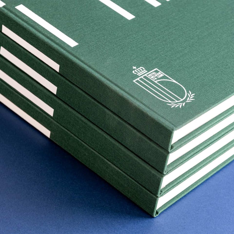 detail van een stapel groene linnen hardcoverboeken met witte folie van belgische voetbalbond